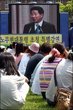 전남대 도서관 앞에 설치된 대형 멀티비전을 통해 시민과 학생들이 더운 날씨에도 불구하고 노 대통령의 강연을 보고있다. 